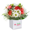 This bouquet radiates a sense of cheerful delight-its painterly mix of coral, peach, and scarlet carnations intertwined with crisp white daisies forms a jubilant celebration perfect for Whetstone's welcoming spirit. Each carnation petal, rich and ruffled, gives off a soft fragrance, while the daisies, with their luminous lime-green centers, sparkle in the natural light. Airy sprays of baby's breath drift gently among the blooms, infusing a feeling of gentle innocence and calm, like an early spring stroll through Swan Lane Open Space. A few purple-tinted buds nestle on the left, offering a promise of blossoms soon to be revealed, while glossy, deep green foliage creates a sturdy embrace, forming a foundation as reliable as Whetstone's own sense of community. The bouquet is presented upright in a flawless white gift bag with sturdy ribbon handles, its fresh, full appearance enhanced by a bright, minimalist white background. Every stem has been thoughtfully placed by a florist who understands the rituals of local giving, making this arrangement ideal for birthdays, congratulatory moments, or a heartfelt show of appreciation that travels easily to loved ones' doors throughout Whetstone.